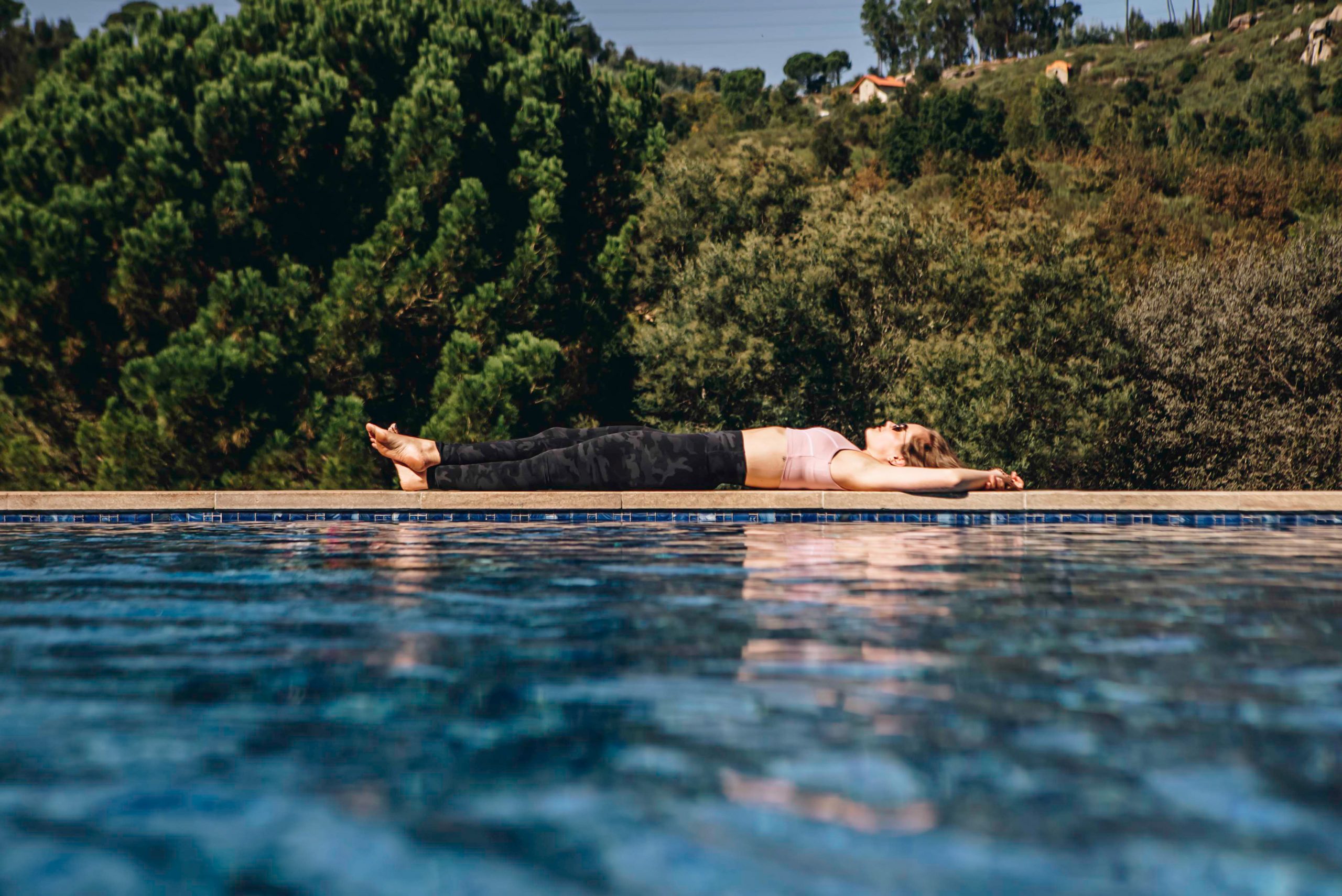 A swimming pool with someone floating on the surface, trees behind